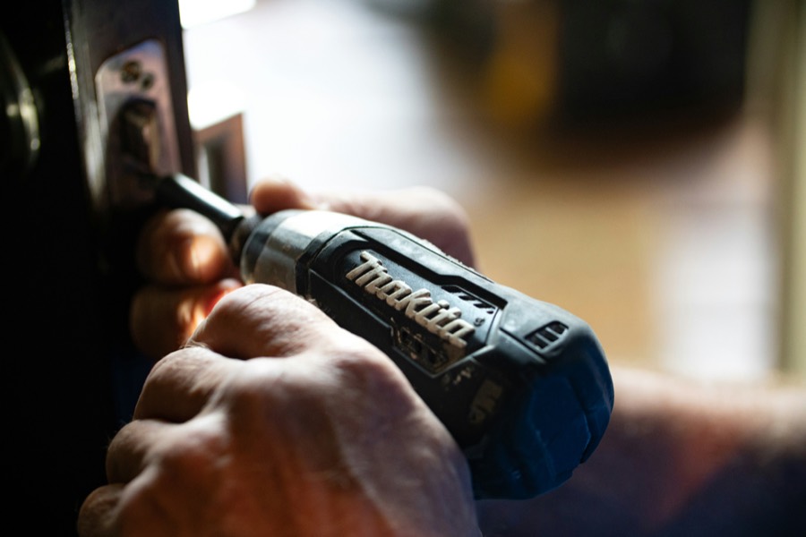 Handyman fixing a door lock with a drill